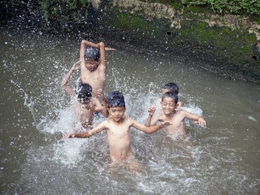 Erkekler 2 Ocak 2026 'da Endonezya' nın Jakarta şehrinde nehirde su sıçratıyor.