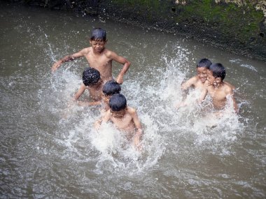 Erkekler 2 Ocak 2026 'da Endonezya' nın Jakarta şehrinde nehirde su sıçratıyor.