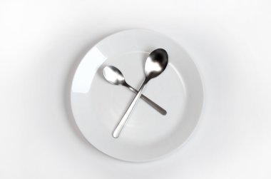 Paslanmaz çelik kaşık ile beyaz bir yüzeye beyaz tabak