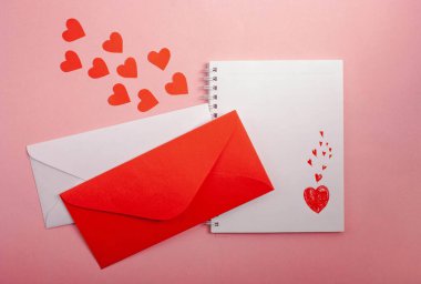 İçinde kalp, zarf, pembe arka planda kırmızı kalpler olan bir defter..