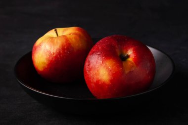 Siyah arkaplanda siyah bir plaka içinde kırmızı elmalar.