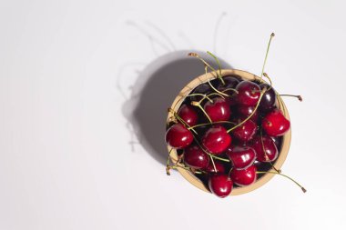 Beyaz arka planda bir kasede taze kirazlar. 