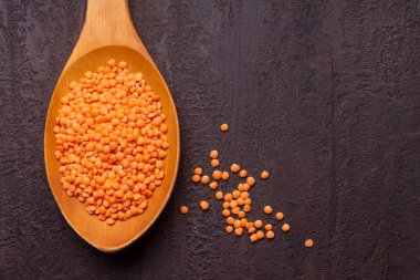 Gri arka planda tahta kaşıkta kırmızı mercimek