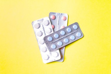Sarı arka planda haplar ve tabletler.