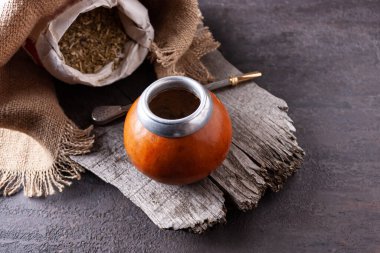 Eski bir ağacın kesiğinde bir koleba, bombilla, bir torba çimen ve bir peçete bulunur..