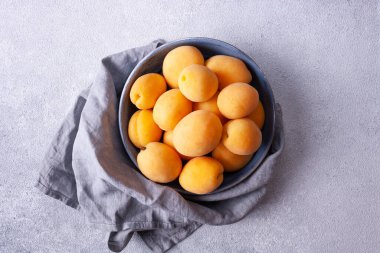 Gri arka planda bir kasede taze kayısılar. en üstteki görünüm.