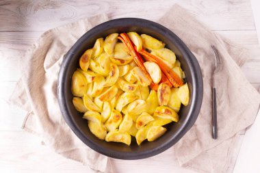 Ahşap arka planda baharatlı ve sebzeli fırında patates. en üstteki görünüm.