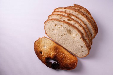 Beyaz arkaplanda kuru üzümlü dilimlenmiş ekmek.