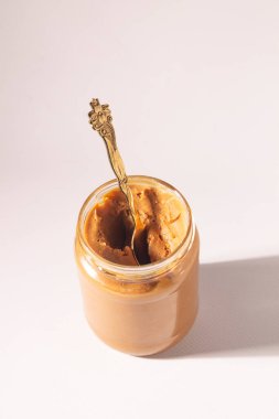 Beyaz arka planda cam bir kavanozda çikolatalı dondurma.