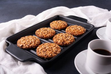 Kahveli ev yapımı kurabiyeler ve siyah arka planda bir fincan çay.