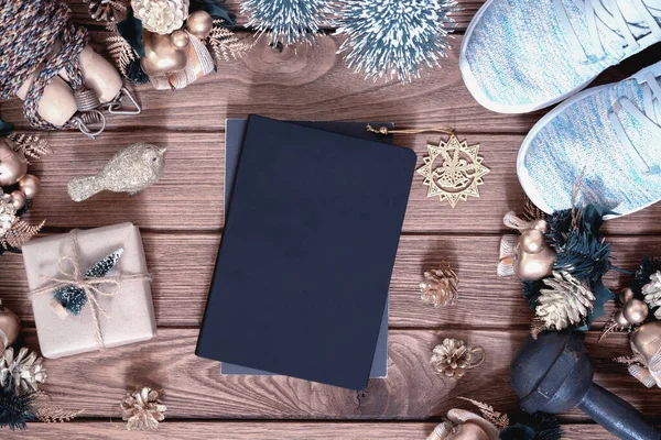 Yeni yıl çözümleri için boş alanı olan boş bir kapak kitabı sağlıklı hedefler konsepti, Noel hediyesi kutusu ve ahşap arka planda sağlıklı sağlık ekipmanları olan Noel süsleri.