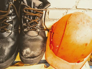 Tuğla arka planda inşaat başlığı ve botları