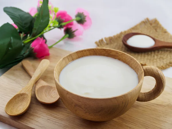 Iogurte grego, leite em xícara de madeira e colher em madeira Imagem De Stock