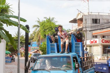 Çocuklar kamyonetin arkasında mavi plastik sandalyelere binmek.
