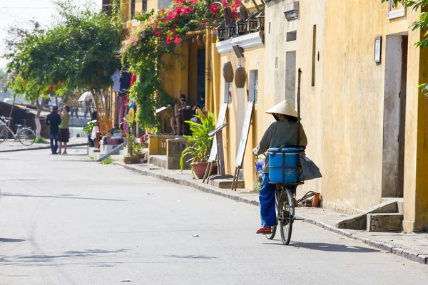 Vieille femme au chapeau conique fait du vélo dans la rue de Ho — Photo