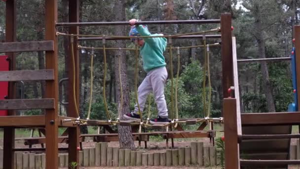 Uma Criança Atravessa Ponte Suspensa Parque Infantil Floresta — Vídeo de Stock