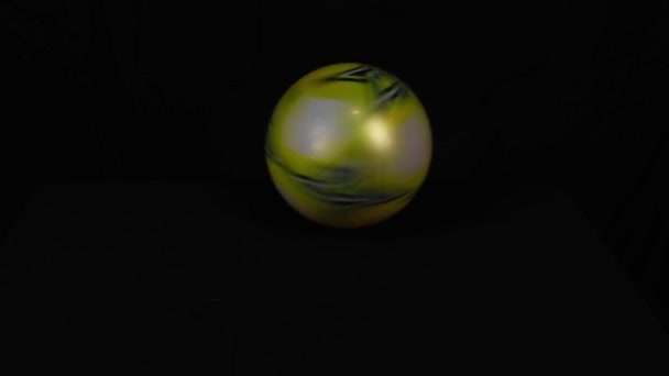 Крутящийся пластмассовый мяч перед черным фоном — стоковое видео