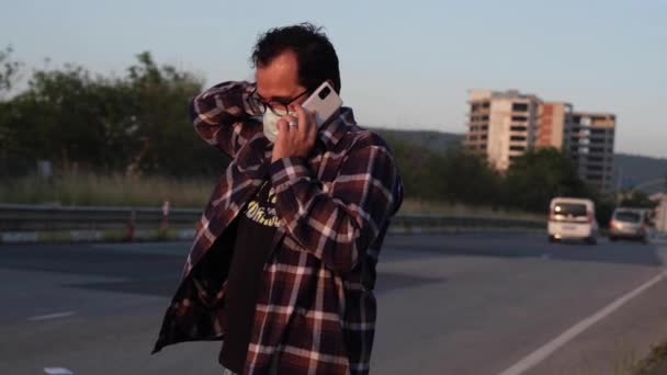 Homem falando ao telefone enquanto espera pelo ônibus — Vídeo de Stock