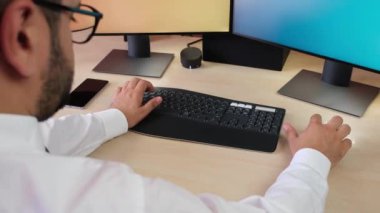 Arka planda bilgisayarları olan bir adam klavye ve fare kullanıyor