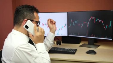 Borsacı, borsa grafikleriyle ilgili telefon görüşmesi yapıyor.