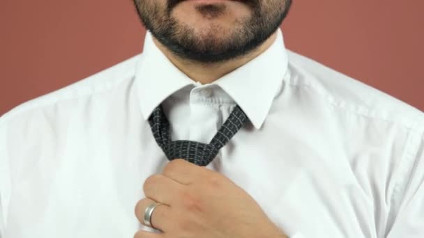 Un hombre con barba y camisa blanca se endereza la corbata — Vídeo de stock