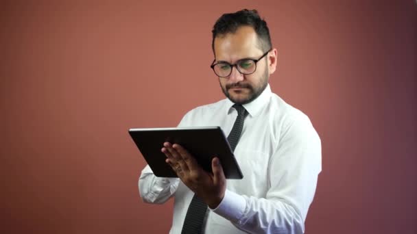 Een zakenman gebruikt een tablet op een steenrode achtergrond — Stockvideo