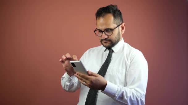 Un Empresario utiliza un teléfono móvil sobre un fondo rojo ladrillo — Vídeo de stock