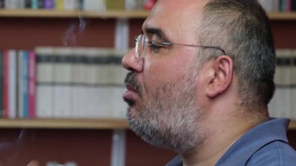 Egy középkorú férfi bent dohányzik. — Stock videók