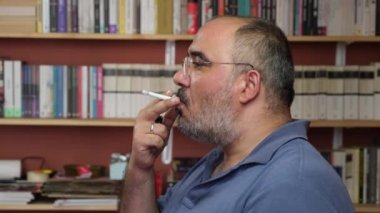 Sinirli orta yaşlı bir adam sigara içiyor..
