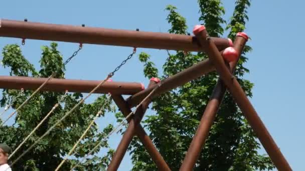 Playground, big swing ropes swing back and forth between blue sky and trees — Stock Video