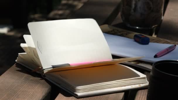 Wind-Notizbuch, die Blätter eines Notizbuchs auf dem Tisch wiegen sich nachts im Wind — Stockvideo