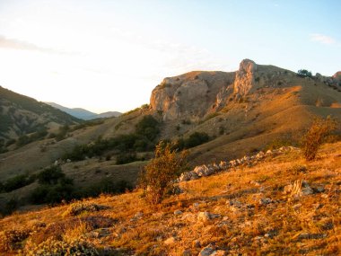 Dağ sıraları yeşilliklerle kaplı. Yeşil alandaki dağlar ve tepeler. Gün batımında dağ manzarası. Yaz, dağlar, gün batımı, akşam, rüzgar, sessizlik, hiç kimse.