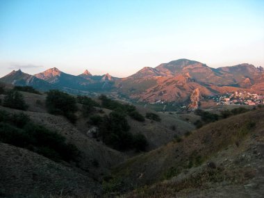 Dağ sıraları yeşilliklerle kaplı. Yeşil alandaki dağlar ve tepeler. Gün batımında dağ manzarası. Yaz, dağlar, gün batımı, akşam, rüzgar, sessizlik, hiç kimse.