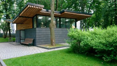 Parktaki küçük bir şehir kulübesinin manzarası. Bir yaz günü yeşil ağaçların arasında bir kulübe şeklinde şehir tuvaleti..