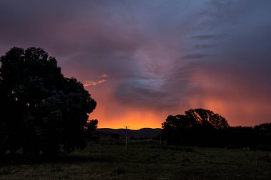 Arjantin 'in orta kesimindeki Buenos Aires Eyaleti' nin az sayıdaki dağlık alanlarından biri olan Sierra de la ventana 'da, gün batımında güneş ışığı ve pembe renklerle karışık bir fırtınanın ardından Arjantin' deki bulutlarla birlikte gün batımında garip bir gökyüzü.