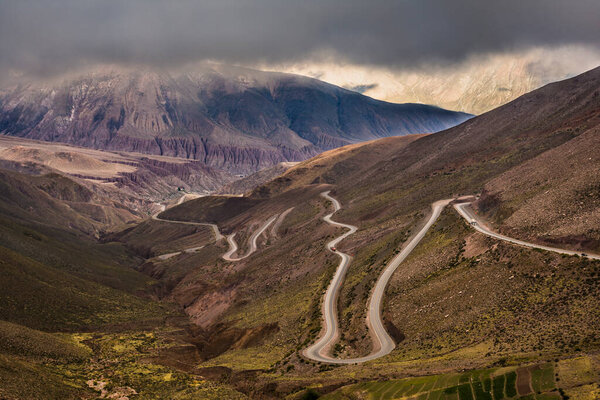 Опасная горная дорога со множеством поворотов между горами в выразительный облачный день. Куэста-дель-Липн, Жужуй, Северная Аргентина.