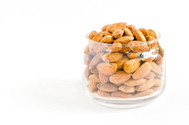 Group of dry organic almond seed pile in glass bowl on white background, ready for healthy food or dessert ingredient