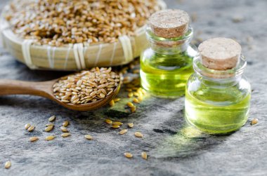 Kapalı organik keten tohumu yağı cam şişede, ahşap kaşıkta biraz tohum ve grunge arka planda sepet ile.