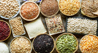 Çeşitli çeşitlerde beyaz, kahverengi ve koyu kahverengi doğal organik tahıl ve tahıl tohumları seramik kasede koyu tonda Grunge arkaplanda, sağlıklı veya temiz gıda malzemeleri veya tarımsal ürün konsepti için