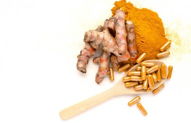 Tahta kaşık üzerinde kapsül paketinde kuru organik zerdeçal tozu ve beyaz zemin üzerinde biraz taze kök ve toz. Tayland bitkisel ilaç ürünü veya doğal tedavi konsepti için