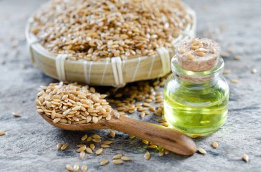 Kapanmış organik keten tohumu cam şişede gerekli yağ ahşap sepette biraz tohum ve grunge arka planda kaşık