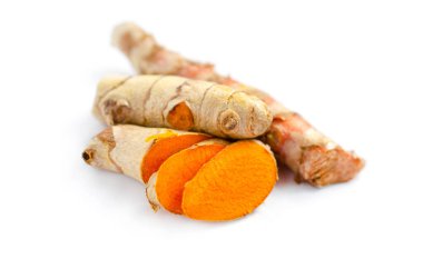 Beyaz zemin üzerinde taze dilimlenmiş organik zerdeçal kökü