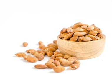 Beyaz arka planda tahta kasede taze badem tohumu yığını.