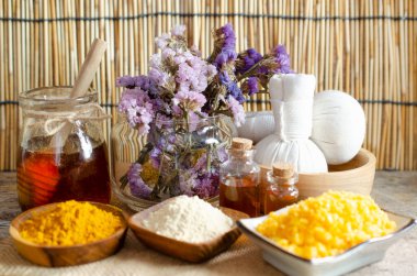 Kapalı organik bal cam kasede spa tuzu, kokulu kuru çiçek, thanaka ve zerdeçal tozu, aroma jeli ve kaplıca dükkanında yumuşak beyaz ve sarı havlu.