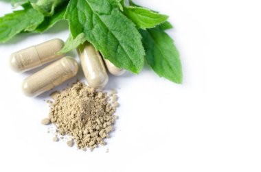 Yeşil Tayland bitkisi tozu, kapsül ve yeşil bitki yaprağı beyaz arka planda. Doğal ilaçlar ya da kimyasal alerjiden korunmak için alternatif tedavi seçenekleri