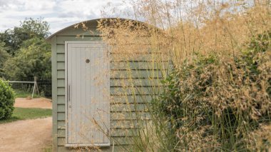 Yeşil renkli çobanlar kıvrımlı çatılı uzun otların arkasında kulübeler