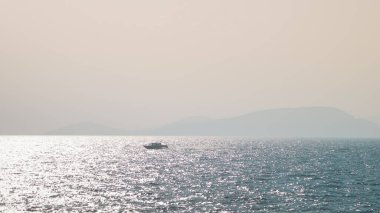 Gün doğumunda küçük bir tekne denizde yüzüyor.