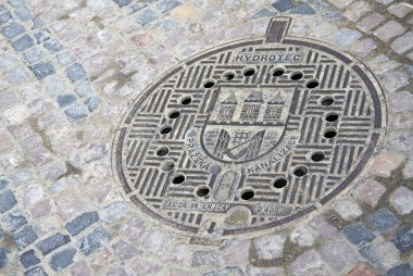 PRAGUE, CZECH REPUBLIC - APRIL 23, 2013: Round steel sewer manhole on old cobblestone road in Prague, Czech Republic