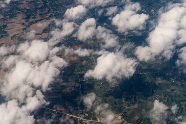 Gökyüzü bulutlarla dolu ve toprağın çoğu yeşil. Bulutlar gökyüzüne dağılmış durumda, bazıları tüm bölgeyi kaplıyor ve diğerleri sadece kısmen görülebiliyor.