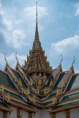 Binanın çatısı altın ve yeşil fayanslarla kaplıdır. Çatı çok süslü ve çok fazla detay içeriyor. Bina açık mavi gökyüzü olan bir şehirde.